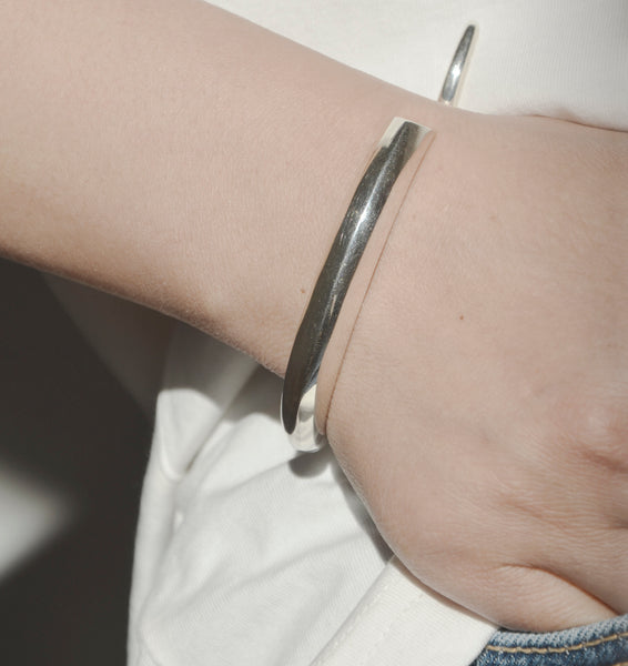 Confident in sculptural minimalist silver bracelet in organic shape.